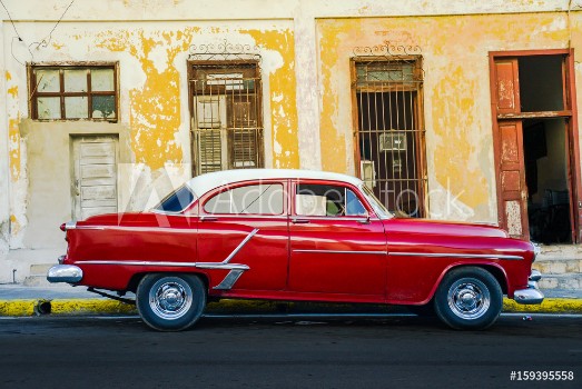 Bild på Vibrant red shiny car and ruined house in Cuba